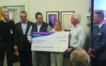 State government officials present a check for $62 million to the Macon County Board of Education on Tuesday.